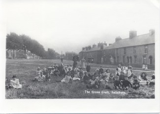 Children on the Greencroft at the start of the twentieth century. A group of about 40 children sitting on the grass of the Greencroft. The photo shows the original layout of that corner of the park, before it was changed with the building of the ring road.